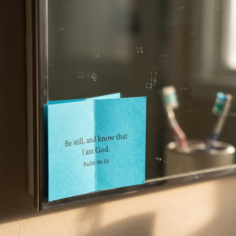 A verse slip tucked into the corner of a bathroom mirror